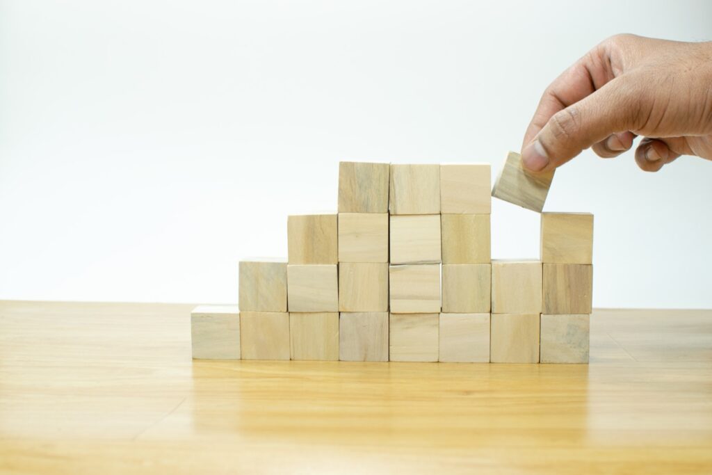 Hand arranging wood block stacking as step stair on wooden table, Business concept for growth success process.